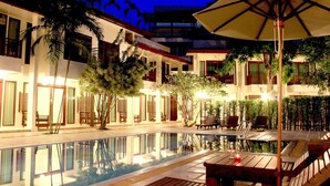 A poolside area with a wooden deck, lounge chairs, and an umbrella. - The Mantrini Chiang Rai (Chiang Rai)