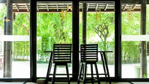 Two chairs facing a large window with a view of greenery outside. - The Mantrini Chiang Rai (Chiang Rai)