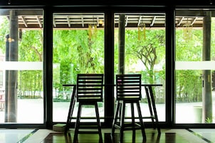 Two chairs facing a large window with a view of greenery outside.