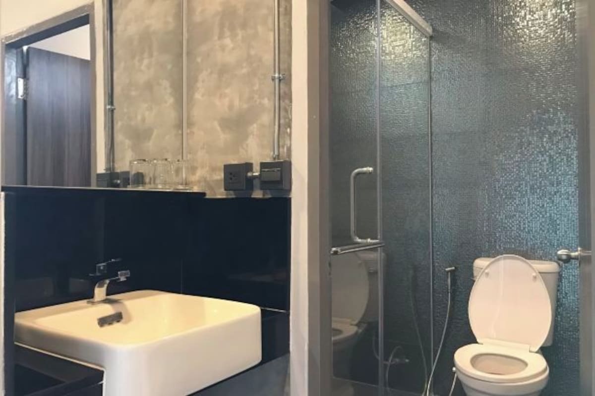 Un baño con lavamanos blanco, cabina de ducha de vidrio y un inodoro.