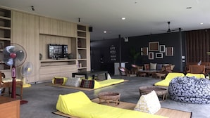 Ein modernes Wohnzimmer mit Flachbildfernseher, Holzregalen und einer schwarzen Wand mit gerahmten Kunstwerken.