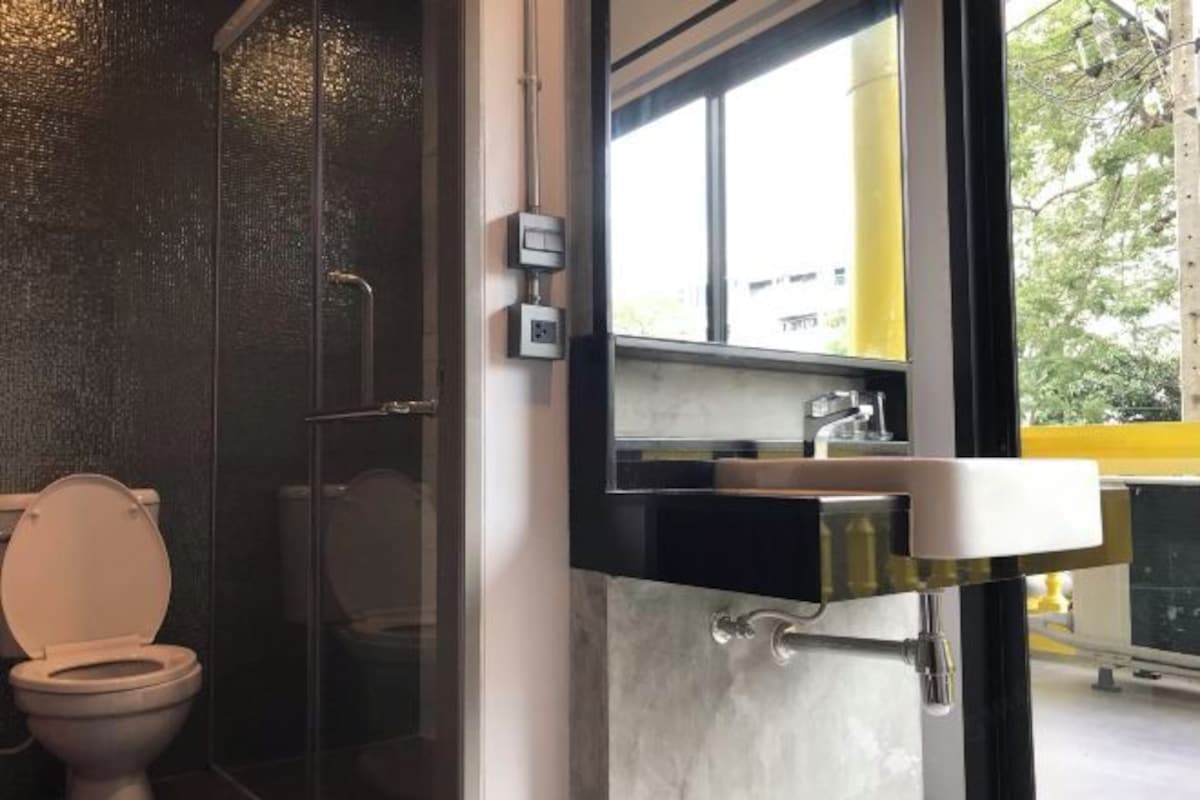 Un baño moderno con inodoro, cabina de ducha de vidrio y lavamanos con espejo.