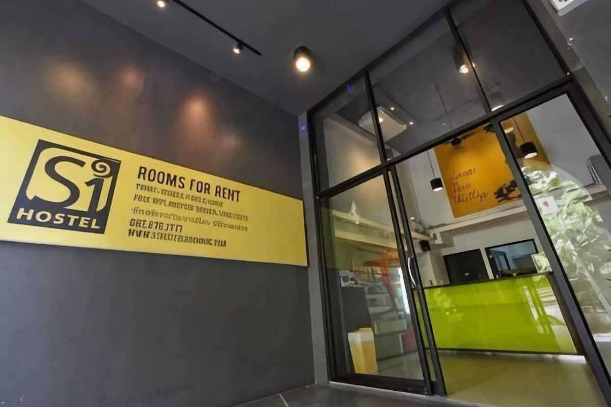 A hostel sign with 'ROOMS FOR RENT' and contact information.