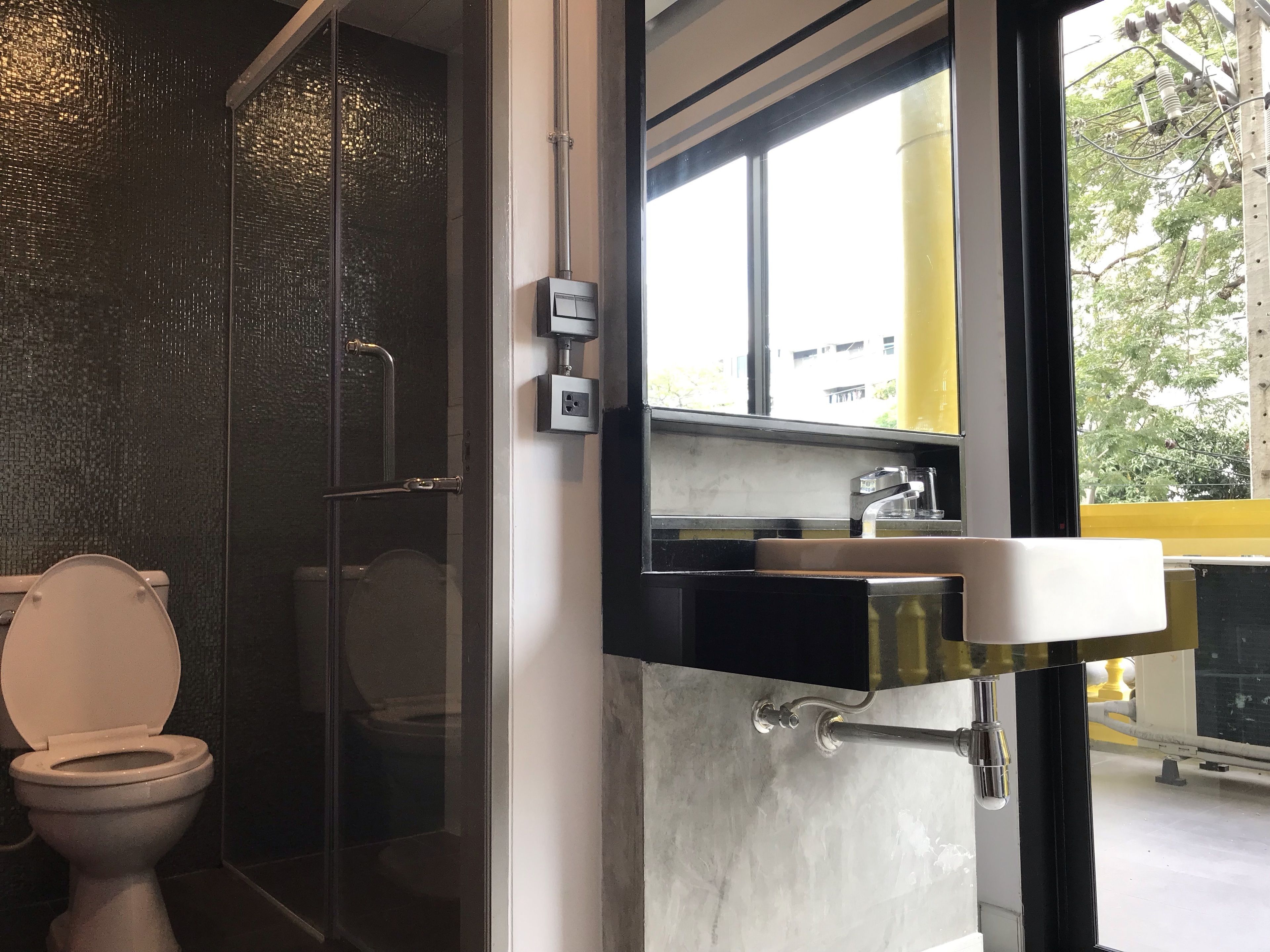 A modern bathroom with a glass shower enclosure, a toilet, and a sink with a mirror above it.