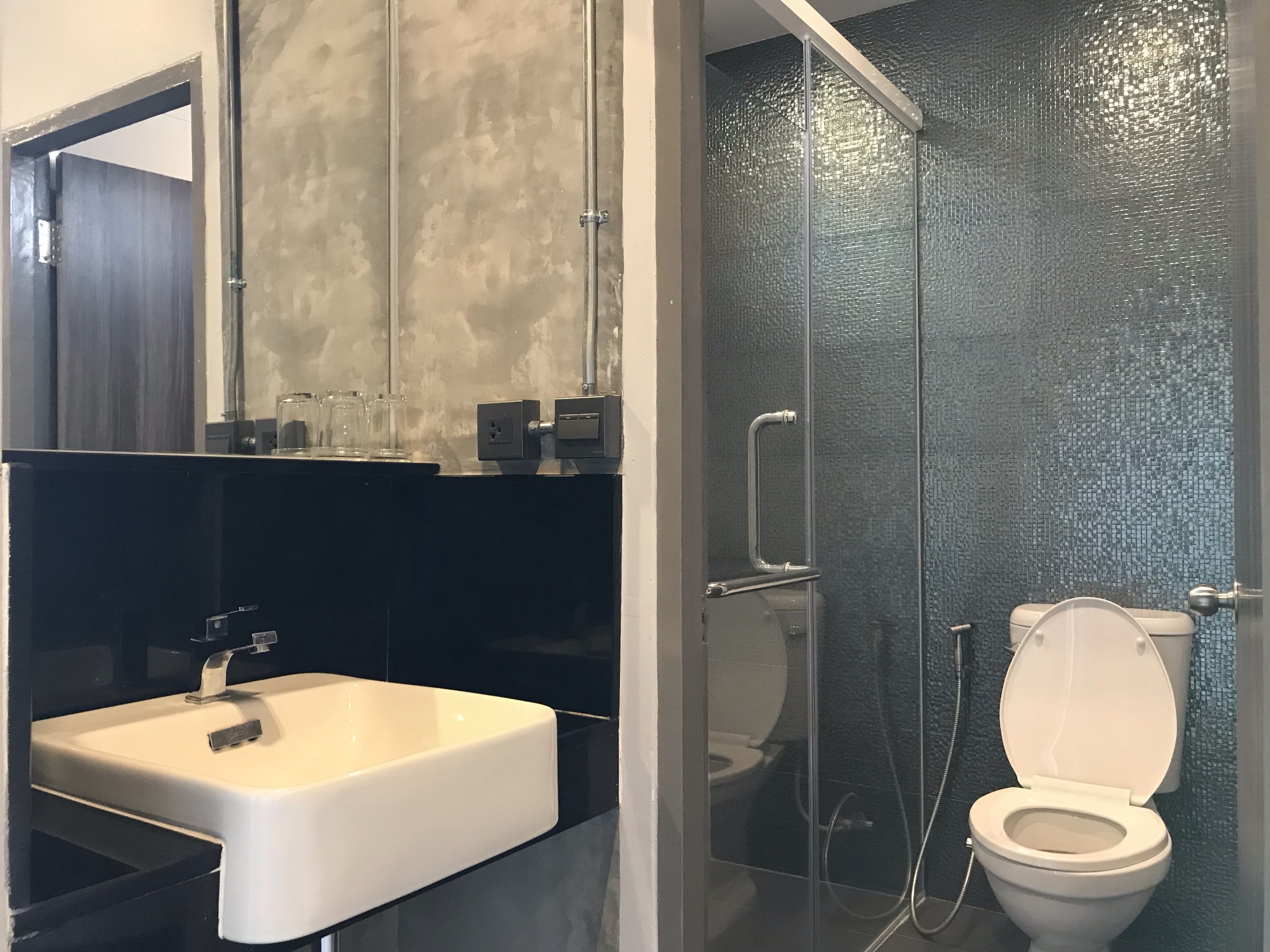 A modern bathroom with a white sink, a glass shower enclosure, and a toilet.