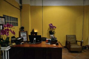 A reception desk with a computer, a clock, and a chair.