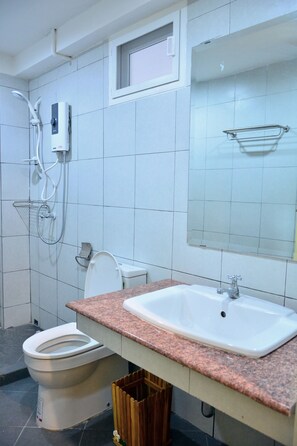 A bathroom with a white toilet, a sink, and a shower.