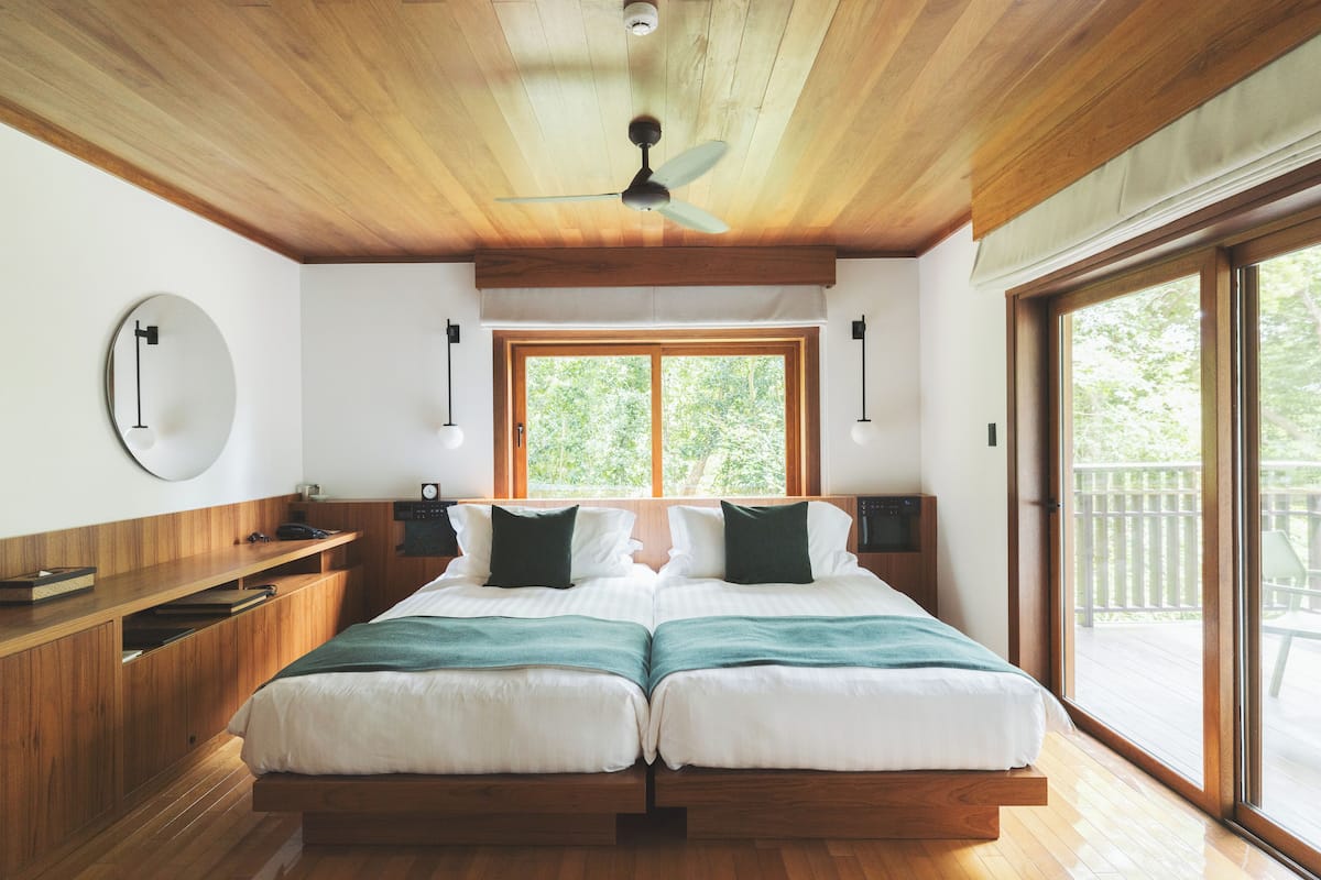 A bedroom with a wooden ceiling, a large window, and a bed with two pillows.