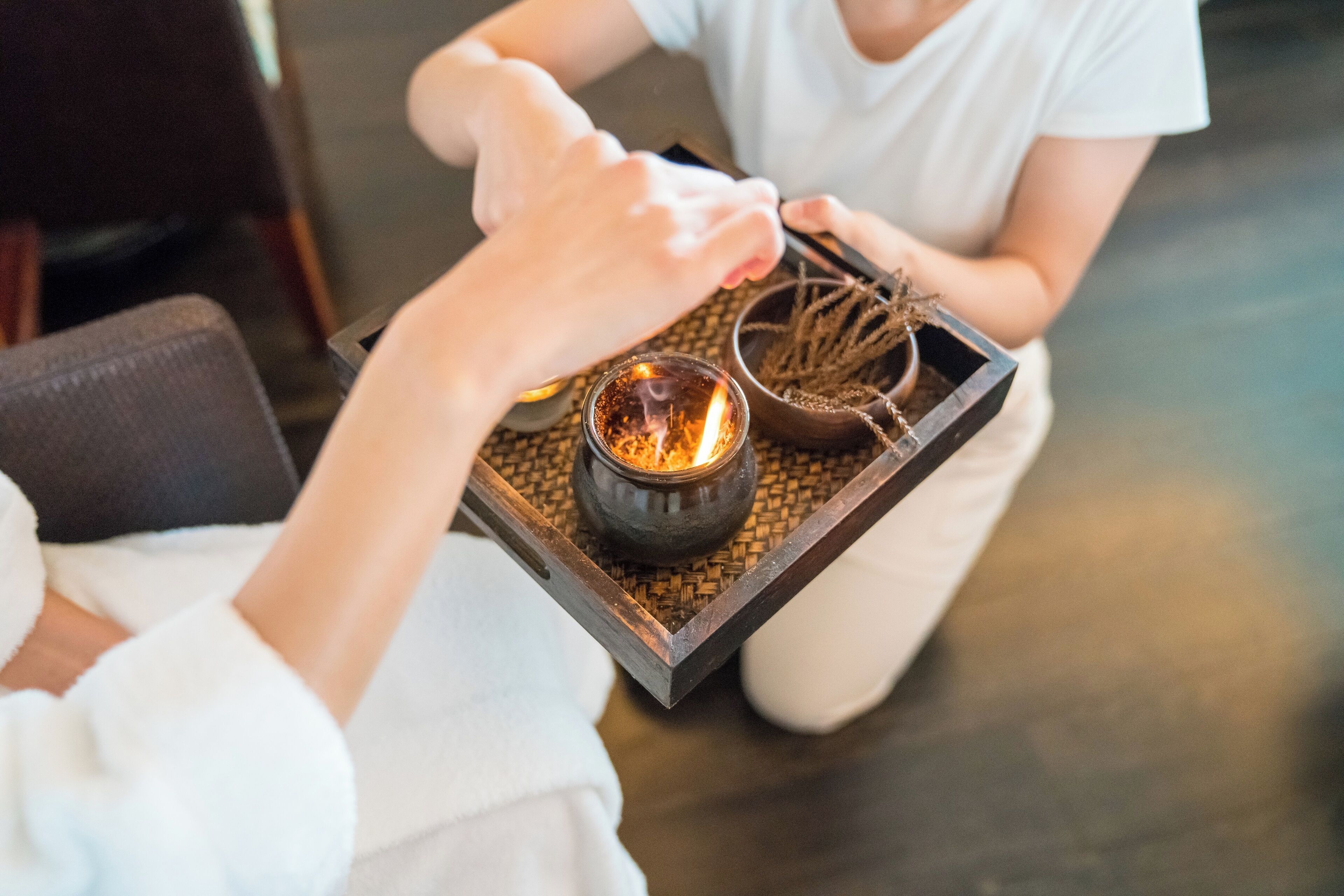 A tray with a candle and a small bowl of dried plants.