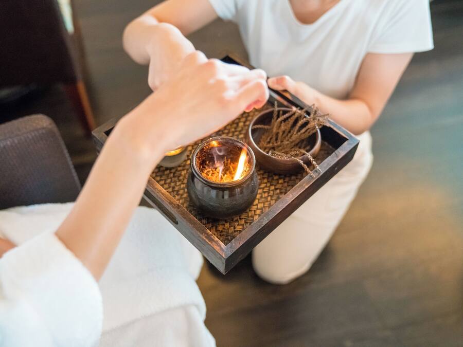 A tray with a candle and a small bowl of dried plants.