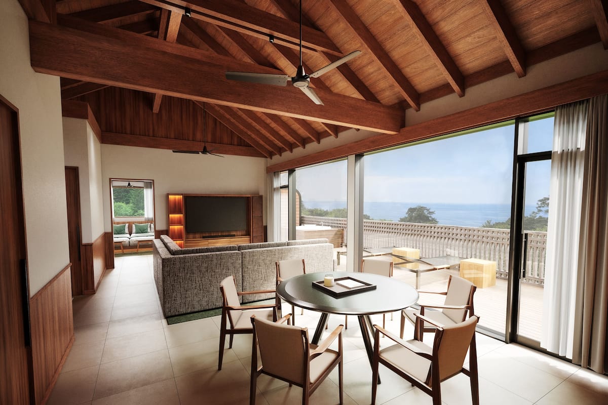 A spacious living area with a large TV, comfortable seating, and a balcony with a view.
