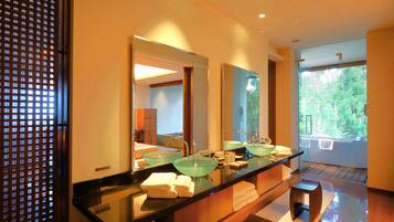 A modern bathroom with a glass sink, two mirrors, and a wooden vanity.