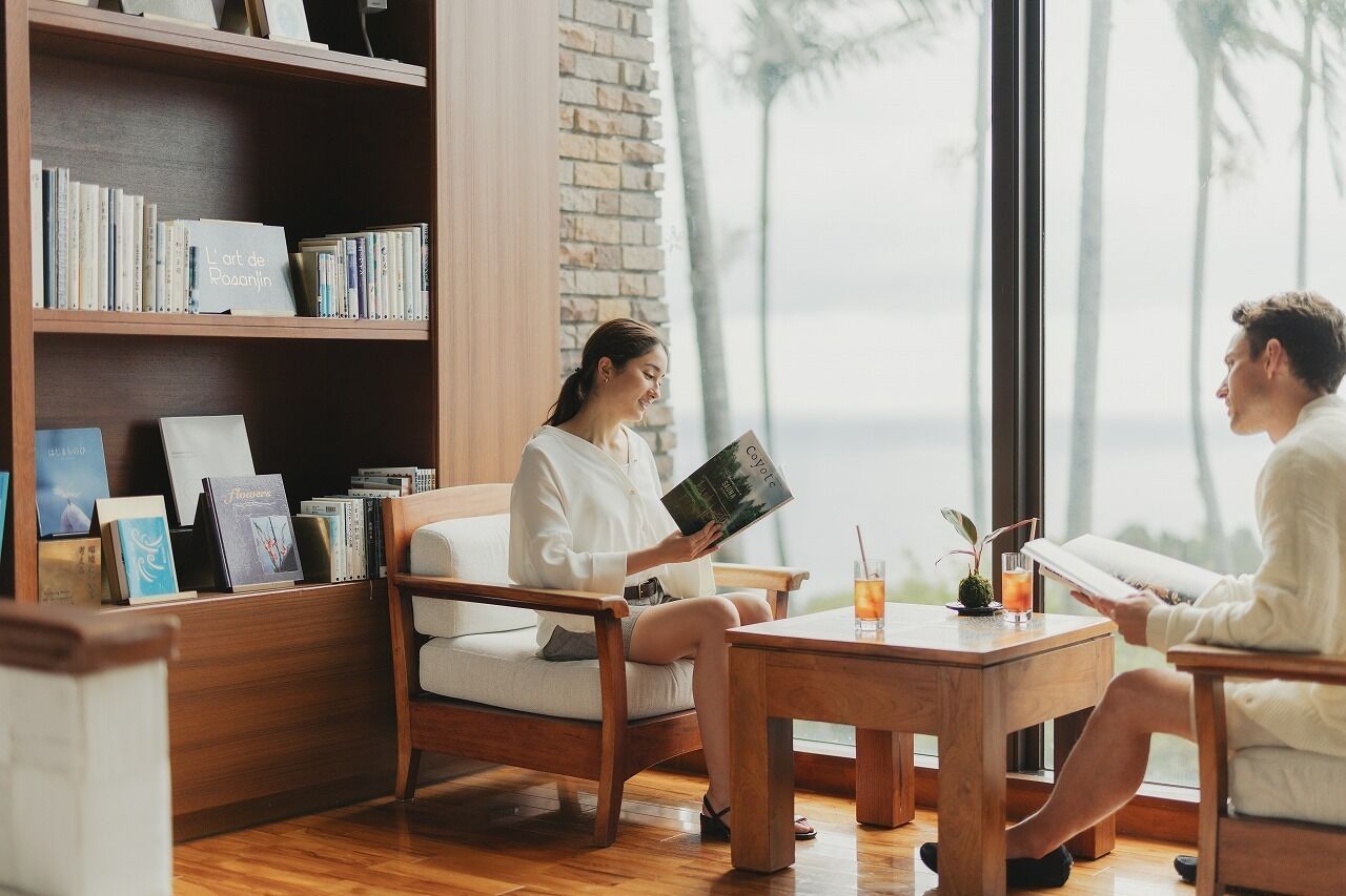 A cozy reading area with a bookshelf, a coffee table, and a view of the outdoors.