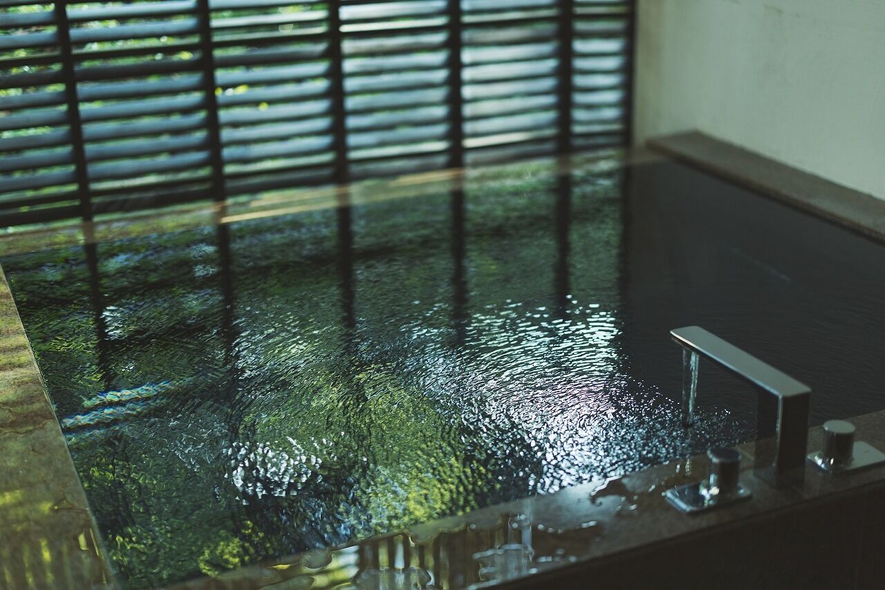 Ein Badezimmer mit einer Badewanne, einem Wasserhahn und einem Fenster mit Jalousien.