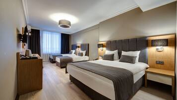 Een moderne hotelkamer met twee bedden, een houten bureau en een grote spiegel.