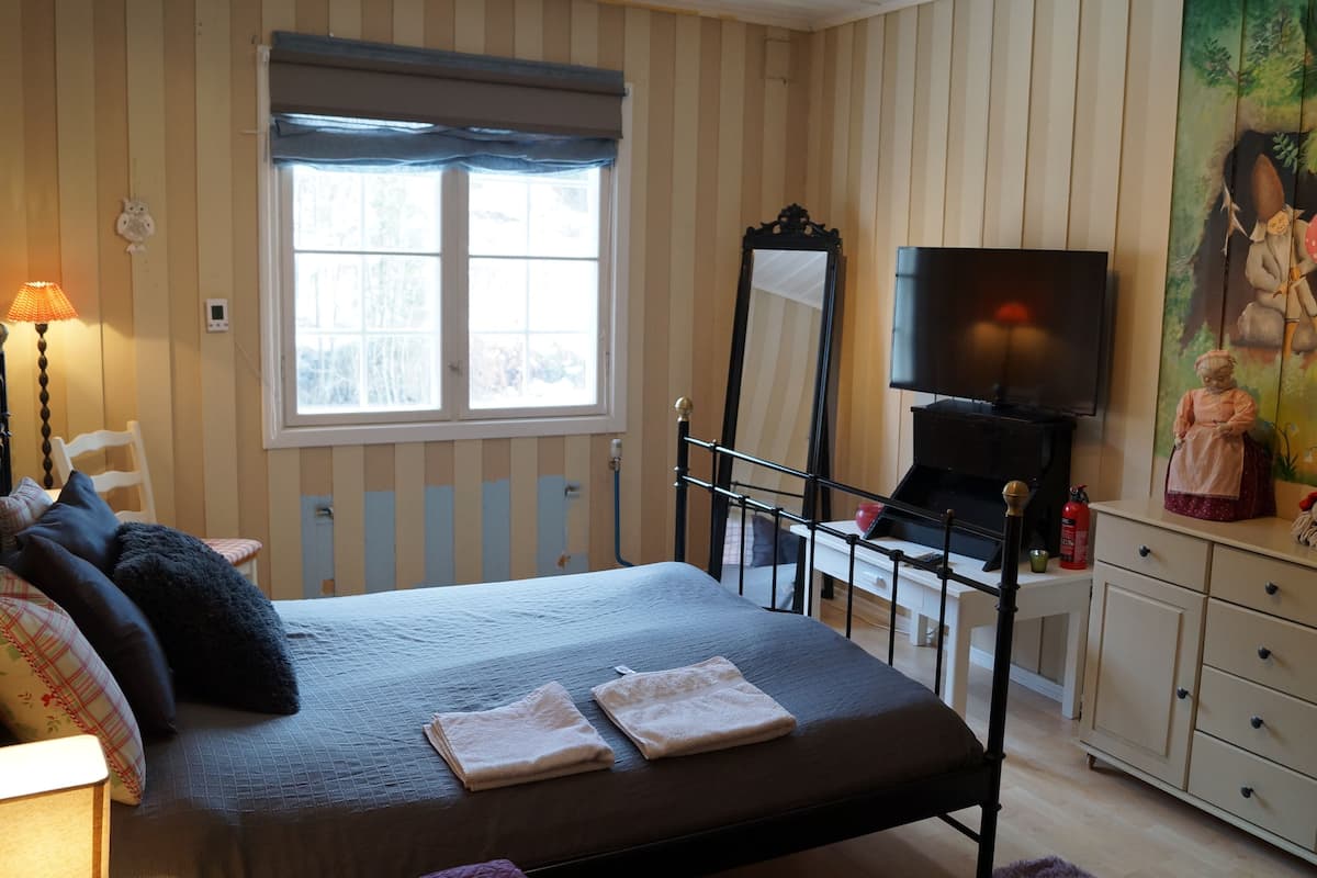 A bedroom with a bed, a television, a dresser, and a painting.