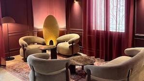 A room with a sofa set, a coffee table, a decorative lamp, and a large window with curtains. - Hôtel Médieval (Avignon)