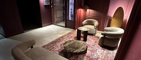 A dimly lit room with a sofa, two armchairs, a small table, and a patterned rug.