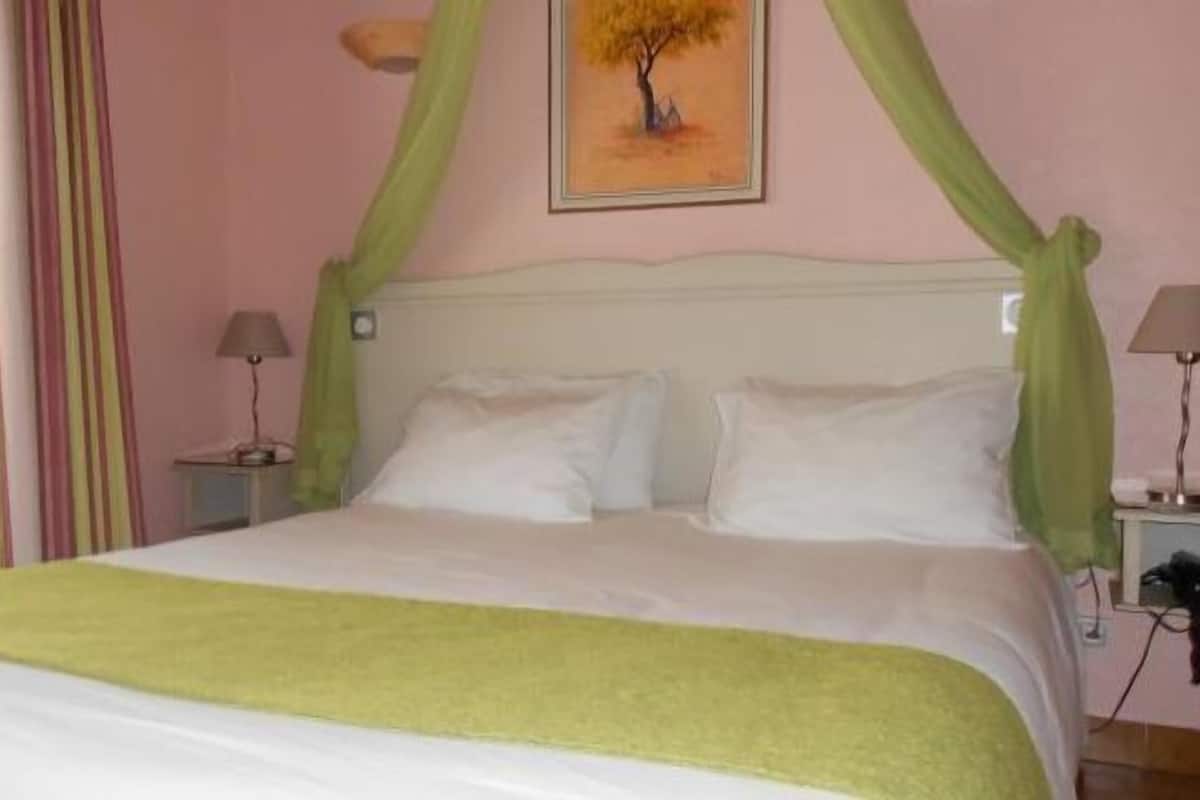 A bedroom with a bed, two bedside tables, a lamp on each table, and a painting on the wall.