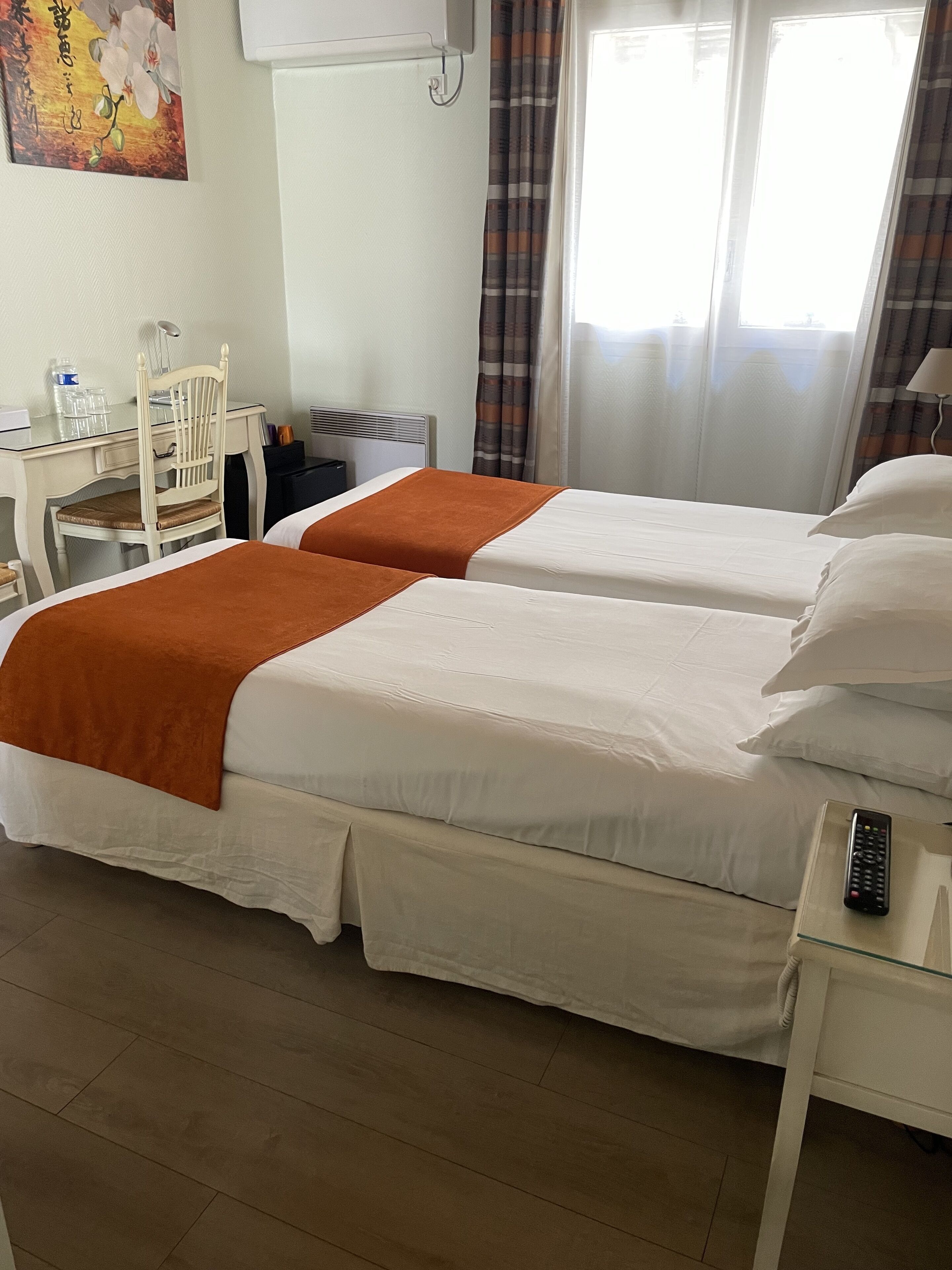 Habitación de hotel con dos camas, un escritorio, una silla, un televisor y una ventana con cortinas.