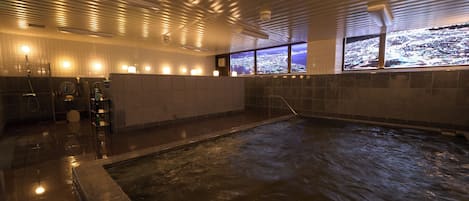 A hot spring bath area with a view of a cityscape through large windows.