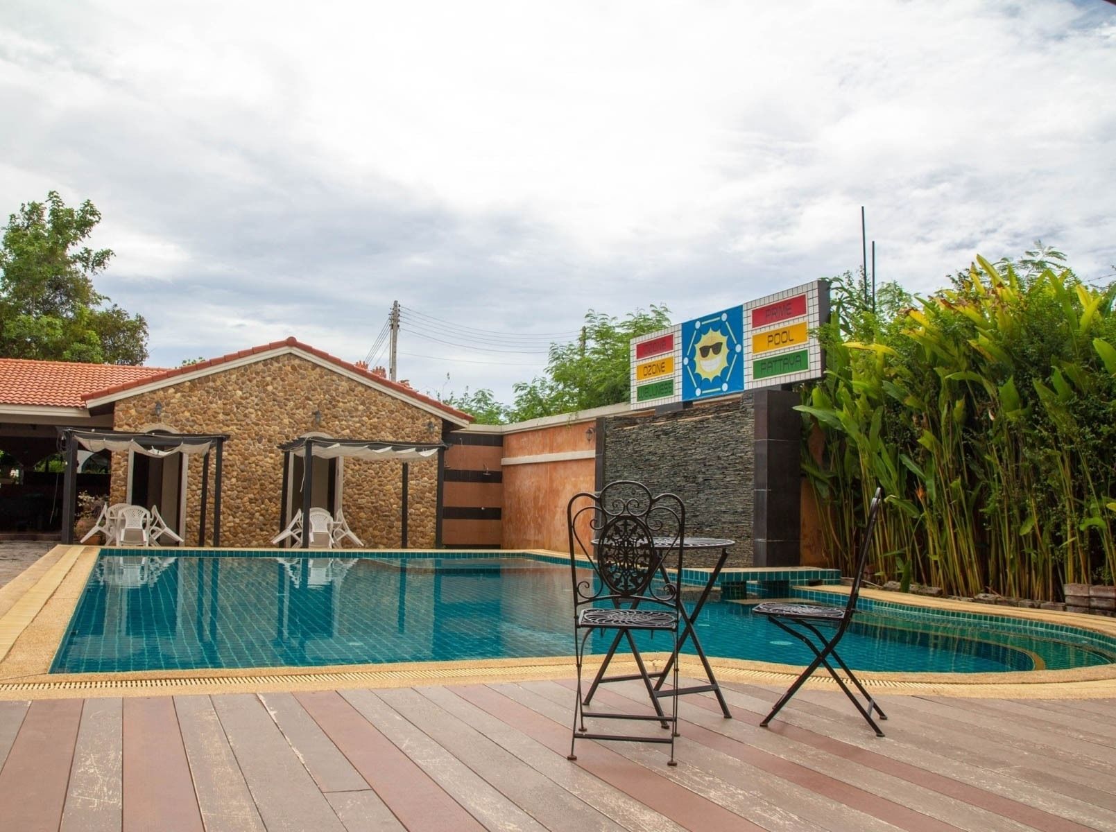 A swimming pool with a stone building and a covered patio area.