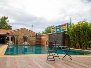 A swimming pool with a stone building and a covered patio area. - Sun Smile Resort Pattaya (Pattaya)