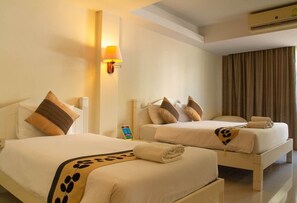 A hotel room with two beds, each with a pillow and a blanket. There is a wall-mounted lamp and an air conditioning unit above the beds. - Sun Smile Resort Pattaya (Pattaya)
