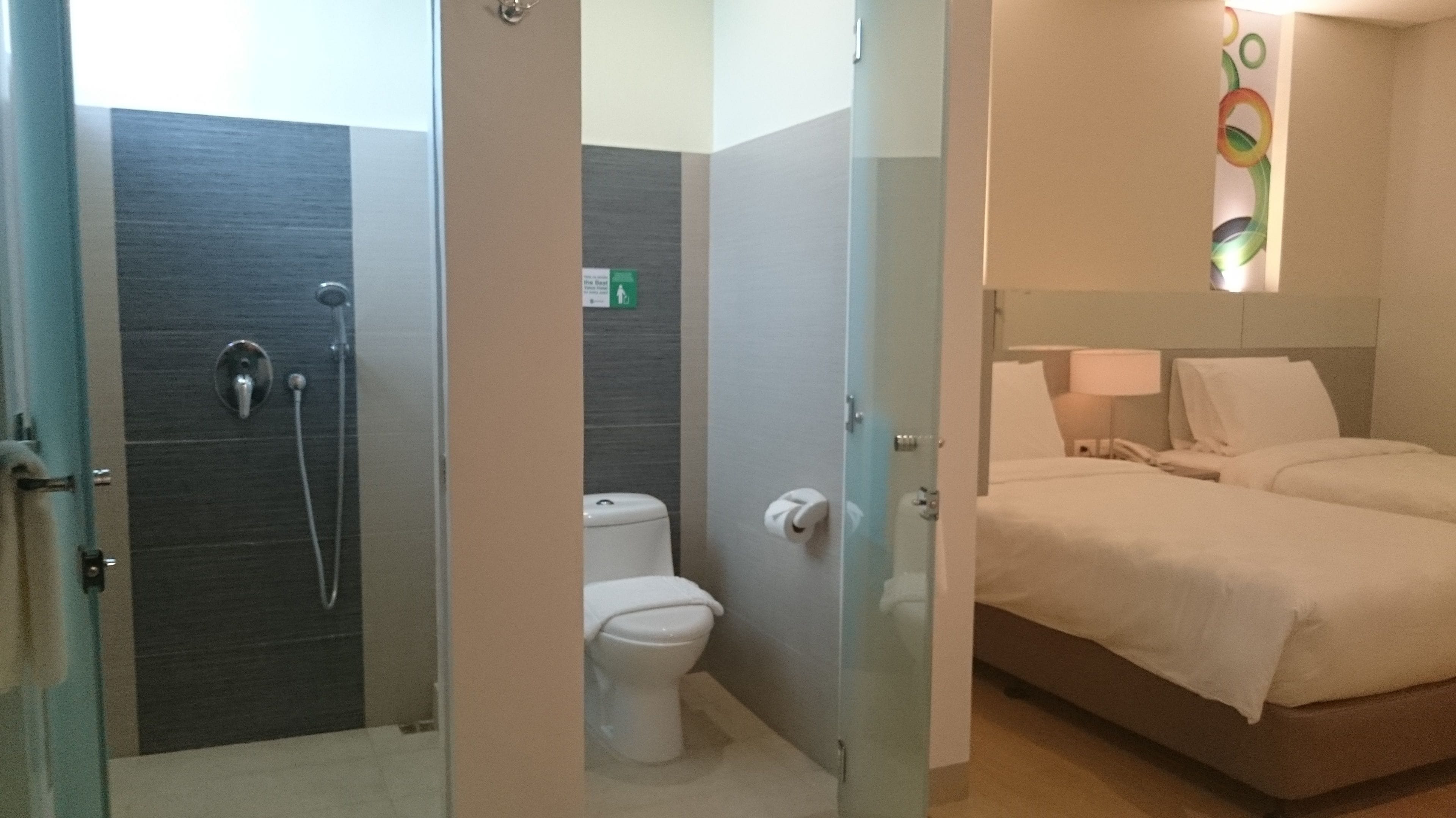 Ein Hotelzimmer mit Dusche, Toilette und einem Bett.