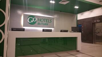 Una recepción con un letrero que dice "GO HOTELS BUTUAN" y un reloj digital que marca las 4:30.