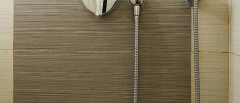 A shower with a handheld showerhead and a wall-mounted control knob.