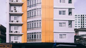 A multi-story building with a curved facade, balconies, and a flat roof with solar panels. - Golden On-nut (Bangkok)