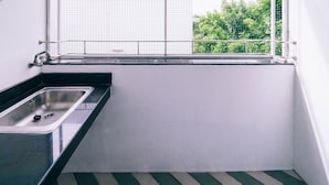 A small kitchen with a sink, a window with a view of greenery, and a herringbone-patterned floor. - Golden On-nut (Bangkok)