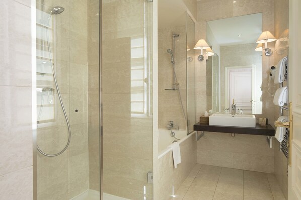 A modern bathroom with a glass-enclosed shower, a sink with a vanity, and a mirror with lights. - Hotel du Danube Saint Germain (Paris)