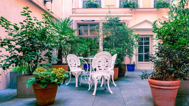 An outdoor patio with white chairs and potted plants. - Hotel du Danube Saint Germain (Paris)