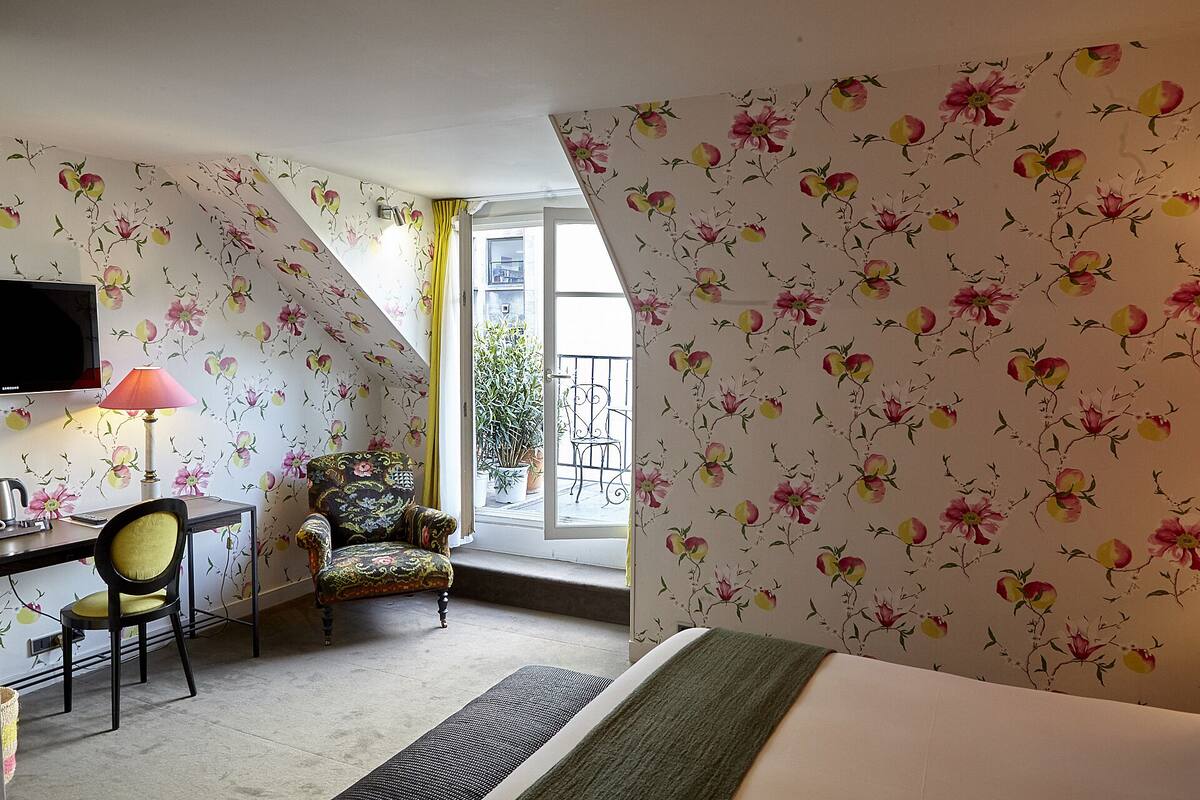 A room with a bed, a desk with a lamp, a chair, and a TV.