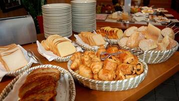 A buffet with various breads and pastries in baskets, plates stacked in the background, and a toaster.