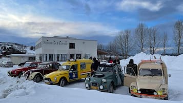 Guests can park their vehicles in front of the Sørreisa Hotel, a modern building with a flat roof and large windows.