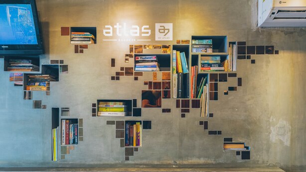 Ett modernt bibliotek med bokhyllor som är arrangerade i ett geometriskt mönster, en tv och Atlas-logotypen på väggen.