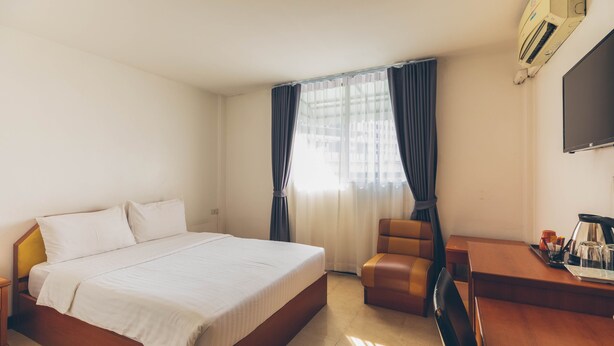 Une chambre d’hôtel dotée d’un grand lit, d’un bureau avec une chaise, d’un téléviseur à écran plat et d’un système de climatisation.