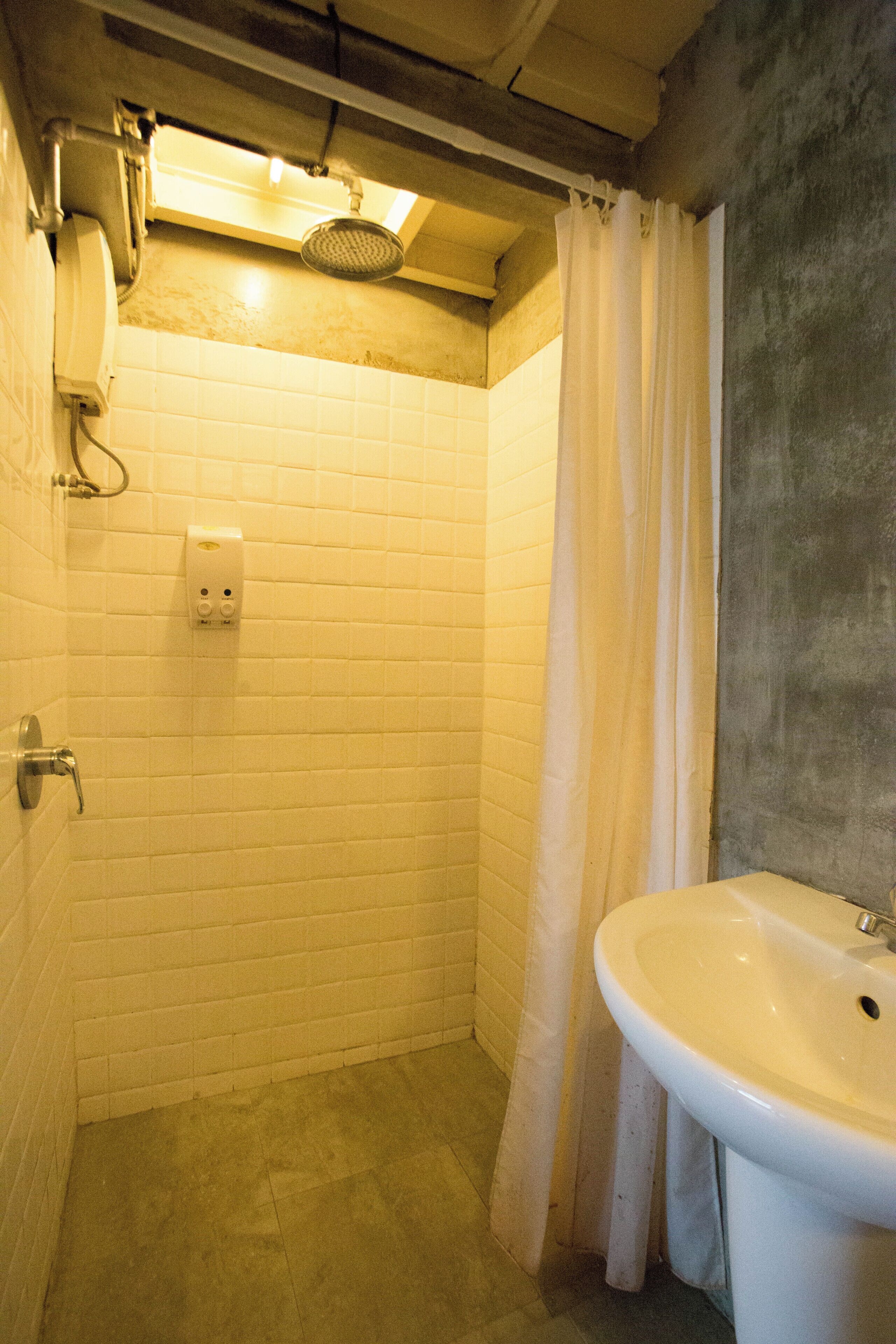 A bathroom with white tiled walls, a shower, a sink, and a curtain.