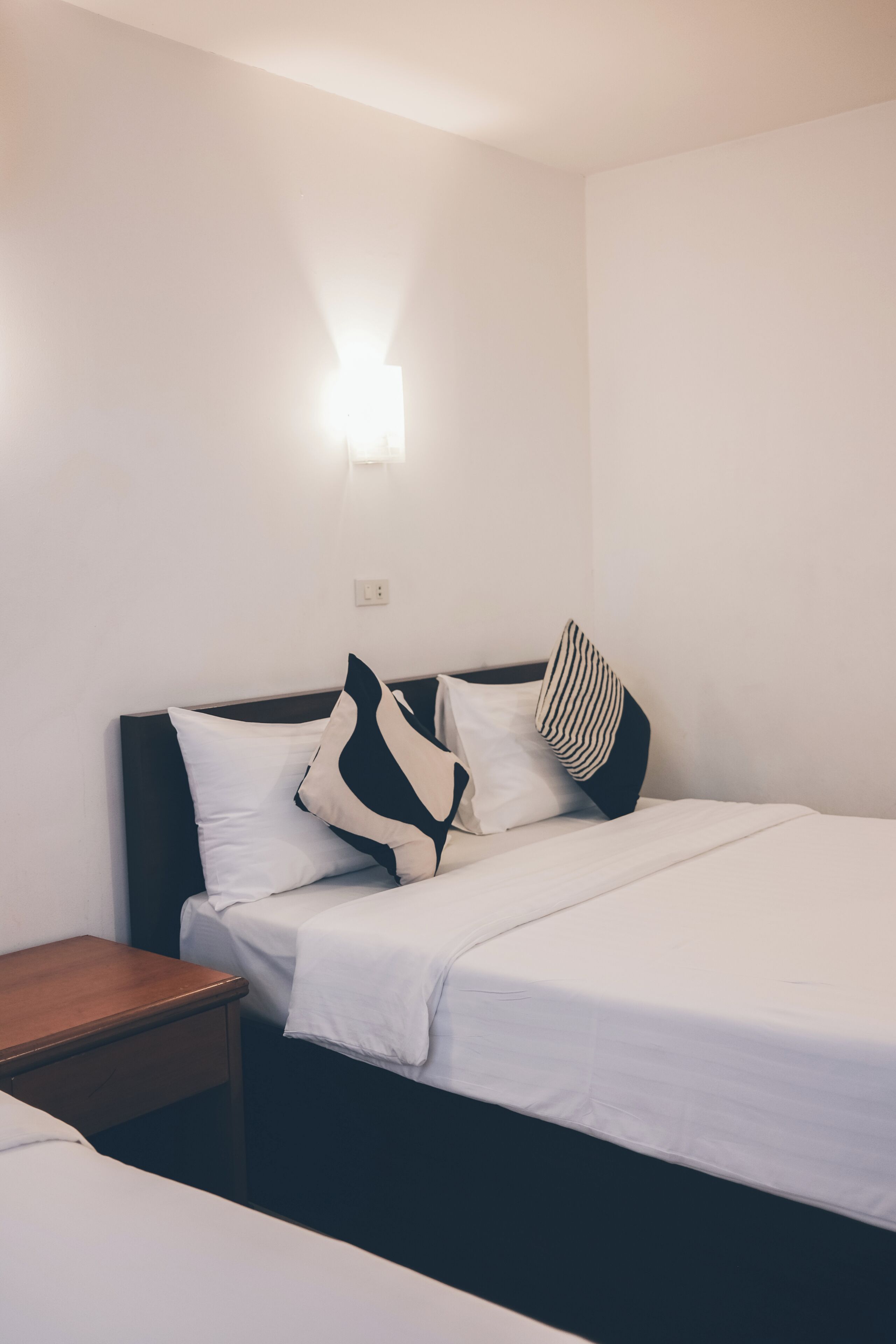 Une chambre d’hôtel avec un lit, une table de chevet et un luminaire fixé au mur.