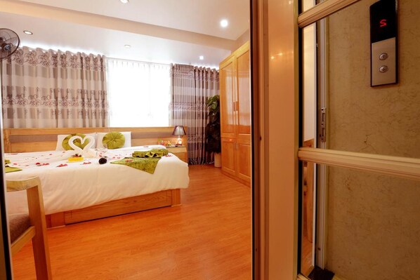 Una habitación de hotel con cama, mesita de noche, lámpara y armario.