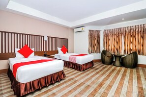 A hotel room with two beds, a wooden headboard, a round table, and a view of the outside. - Collection O JA Siam City (Pattaya)