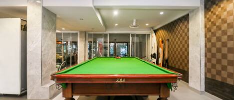 A pool table in a modern indoor setting with a glass partition and a checkered wall.