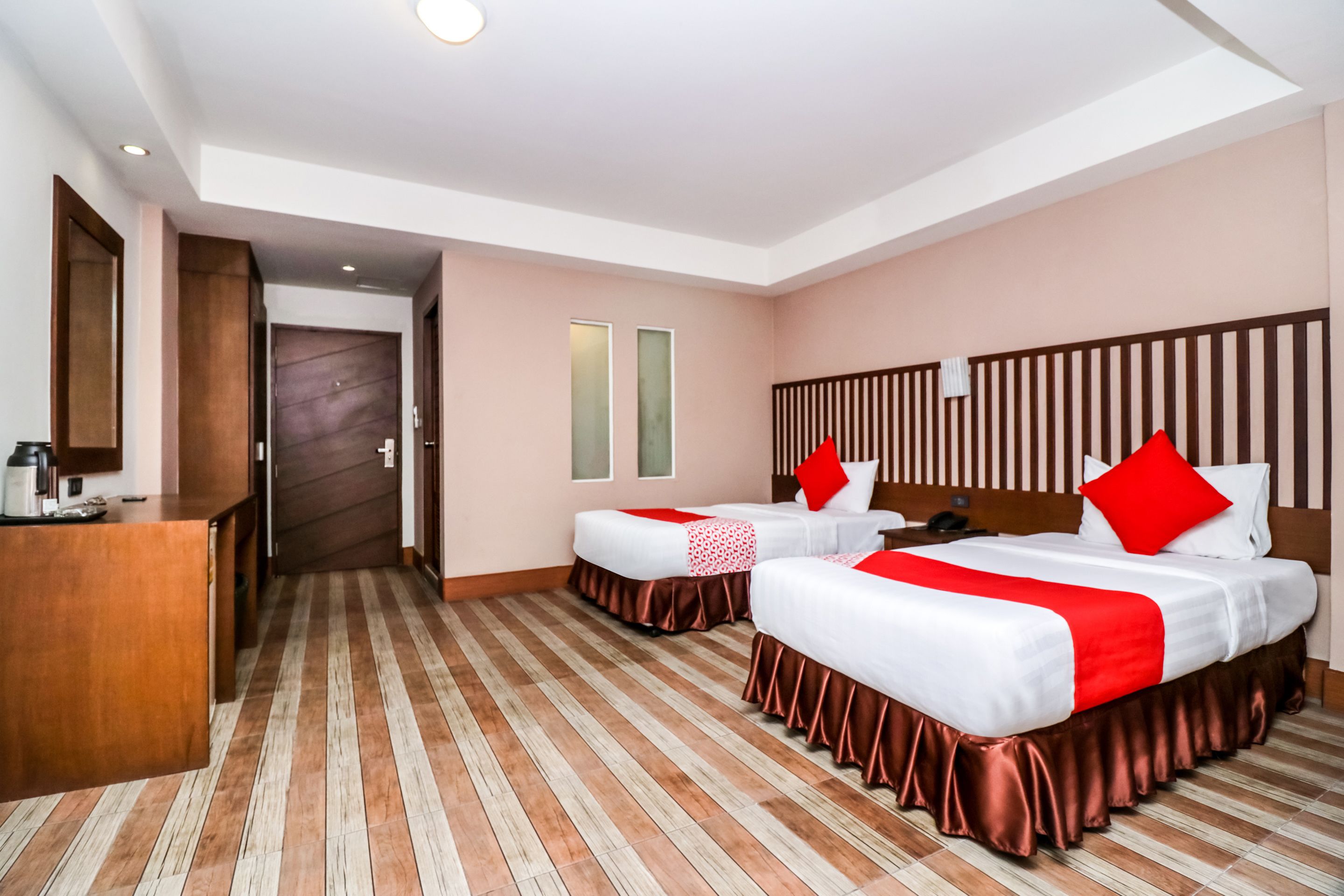 A hotel room with two beds, a wooden desk, and a large mirror.