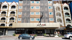 Een hotel met meerdere verdiepingen, een centrale ingang, balkons en een bord met J.A. SIA erop.