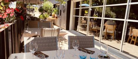 An outdoor dining area with wicker furniture, glass tables, and blue-tinted glasses.