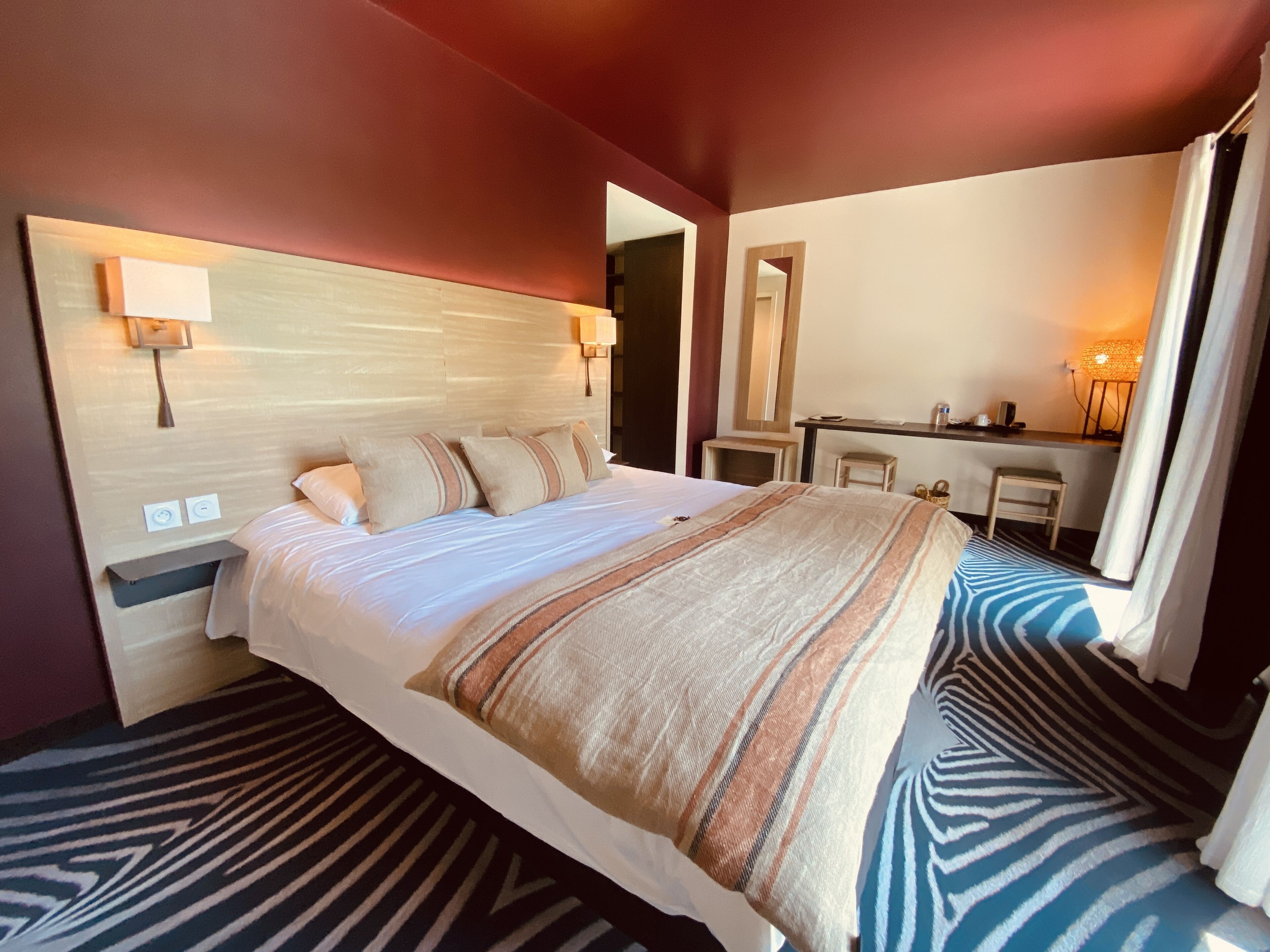 Une chambre d’hôtel avec un grand lit, des lampes de chevet, un bureau et un miroir.