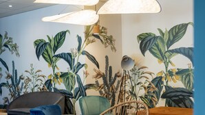 Un área de descanso moderna con un sofá azul, un sillón de mimbre y una pequeña mesa blanca.